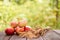 Red apples lie on a wooden board with dry spikes. Green blurred background