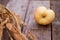 Red apples lie on a wooden board with dry spikes. Green blurred background. Close-up