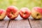 Red apples lie on a wooden board with dry spikes. Green blurred background. Close-up