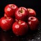 red apples resting atop a glossy black surface, each one glistening with a layer of water droplets