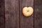 Red apples shepe heart lie on a wooden board with dry spikes. Green blurred background