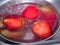 Red apples in water, in stainless steel bowl with a drop of water