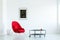 Red armchair next to industrial table in simple white apartment