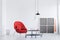 Red armchair with pillow next to industrial coffee table in bright living room interior