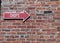 Red Arrow Sign on a Brick Wall Pointing to Shops