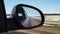 Red automobile in motion. View in the rear view side mirror of a auto, driving a red car along the track,