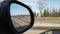 Red automobile in motion. View in the rear view side mirror of a auto, driving a red car along the track,