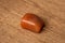 Red aventurin quartz gemstone in different tones in orange red and yellow on wooden underground