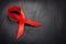 Red awareness ribbon on a dark desk. HIV AIDS