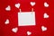 A red background from felt with white paper. Composition with hearts and place for writing a message. Background with place for