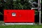 red backup power emergency generator mounted on a green lawn with green trees.