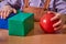 A red ball and a blue cube in the hands of a child