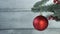 A red ball hangs on a Christmas tree branch. Christmas decor.