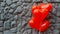 Red balloon heart on a background of gray stone.