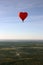 Red balloon in the shape of red heart hovers over the terrain