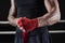 Red bandages on the hands of a kickboxer against the background of the ropes of the ring. The concept of mixed martial arts