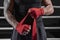 Red bandages on the hands of a kickboxer against the background of the ropes of the ring. The concept of mixed martial arts