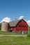 Red barn with brown shingled roof and  old silo on a farm