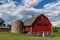 Red barn with brown shingled roof and  old silo on a farm