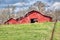 A red barn on a hilltop on a large farm.