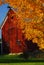 Red barn surrounded by yellow fall leaves in New England