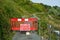 Red barrier and a sign banning the entrance of a narrow road to the forest