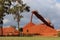 Red bauxite falling off conveyor onto huge red pile of bauxite near Weipa QLD