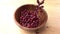 Red beans falling to a wooden bowl on wooden board.