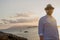 Red-bearded man of European appearance in the golden rays of the sun is at dawn against the backdrop of the sea and islands