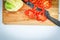 Red bell pepper, cut into slices, cauliflower, ceramic knife lie on a wooden Board