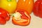 Red Bell Pepper sliced in half with various colored Paprika in background on maple Board