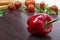 Red bell peppers on a background of tomatoes. The red peppers on a cinnamon wooden background