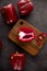 Red bell  peppers on wooden cutting board on black and dark grey background. Green pepper sliced and chopped on wooden chopping