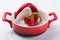 Red bent pepper lies in a red saucepan, on a white background, spicy food