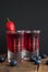 Red berries liqueur in shot glass isolated on black background and wooden table. Homemade alcohol drink concept.