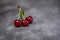 Red berries of ripe cherries with green leaves on a black craft background. Close-up photo of a berry.