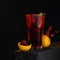 Red berry citrus cocktail. Glass of drink on black background. Orange basket with berries on table. Soft focus. Copy