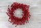 Red berry holiday wreath on rustic white wooden boards