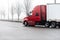 Red big rig semi truck with dry van semi trailer running on the foggy road