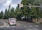 Red big rig tipper truck standing on the crossroad with traffic light and green trees