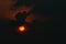 Red big sun in dark clouds. Devil sunset. Horror view of sun in black clouds sky. Summer sunset. Fiery sun in the evening. Nature