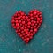 Red bilberry in heart shape on green background