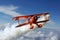 Red Biplane Flying Through Blue Cloudy Sky