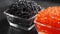 Red and black caviar rotated over black background. Close-up salmon caviar rotation. Delicatessen.