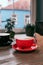 Red and black ceramic cups of cappuccino on wooden table inn a cafe. Mockup for your design.