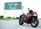 Red black motorcycle modern style parked on road with message Let\\\'s go Travel on green roadsign background