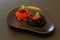 Red and black. Red salted salmon caviar and black caviar of sterlet with mint leaves on black ceramic plate of unusual shape on
