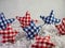 Red and blue checkered fabric covered stars sitting on a bed of white paper shreds with a plaster background for 4th of July,