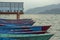 A red blue green wooden boats at the pier on the water in cloudy weather. lake on the background of the mountains