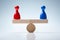 Red And Blue Pawn Figures On Wooden Seesaw